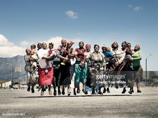 south africa, cape town, langa, group portrait of girls and women with children (2-4) jumping - south africa stock pictures, royalty-free photos & images