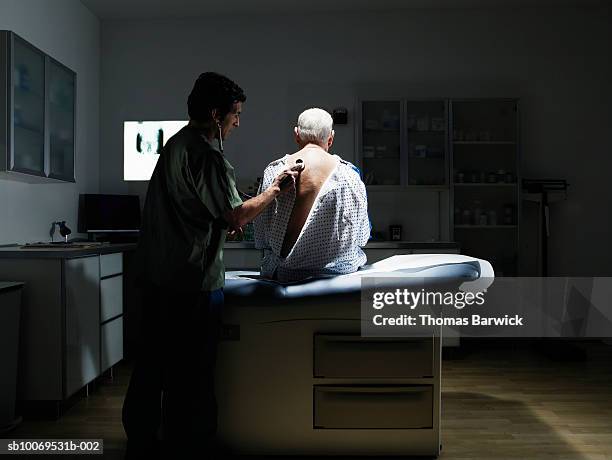 doctor examining patient with stethoscope - tavolo da visita foto e immagini stock