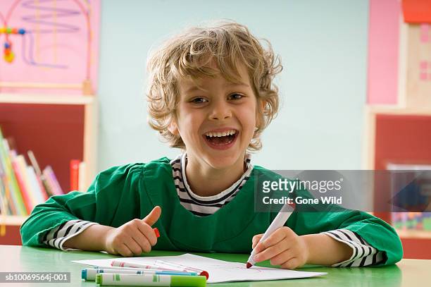 boy (4-5) drawing picture at desk in classroom, portrait - boy curly blonde stock pictures, royalty-free photos & images