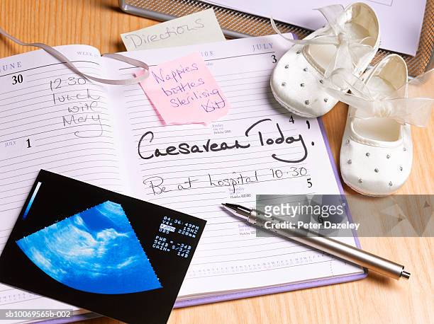 diary and pen on desk with baby booties, high angle view - caesarean section stock pictures, royalty-free photos & images