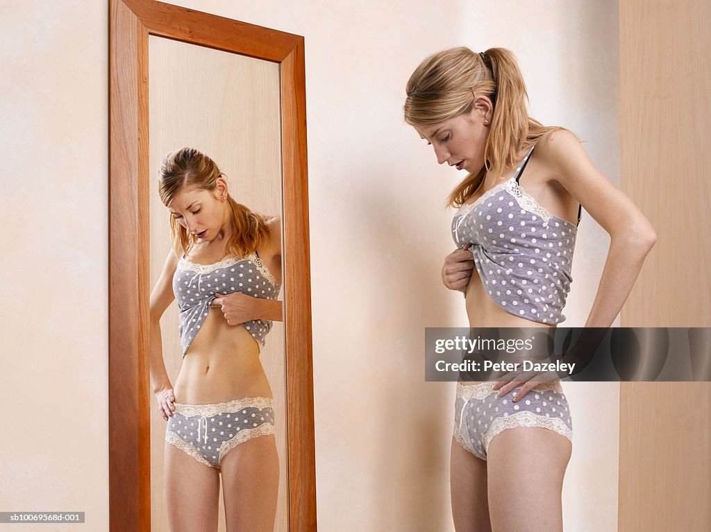 Young woman standing in front of mirror