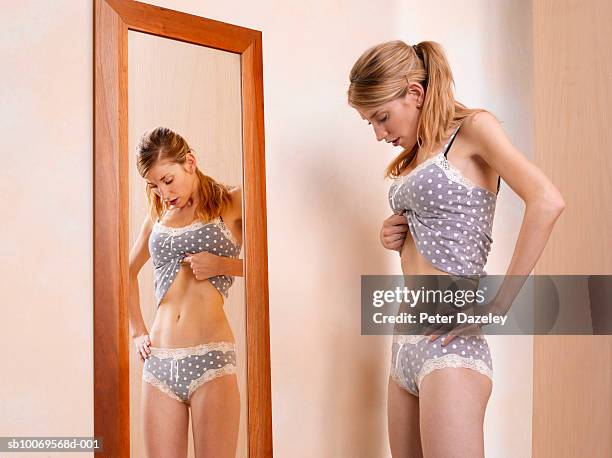 young woman standing in front of mirror - magersucht stock-fotos und bilder