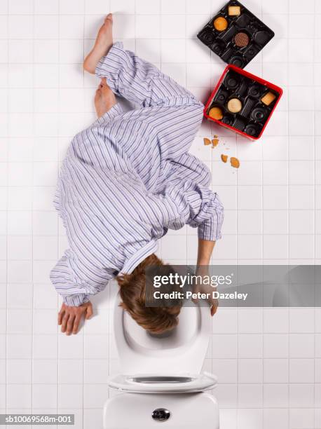 young man vomiting into toilet bowl, directly above - bulimie stock pictures, royalty-free photos & images