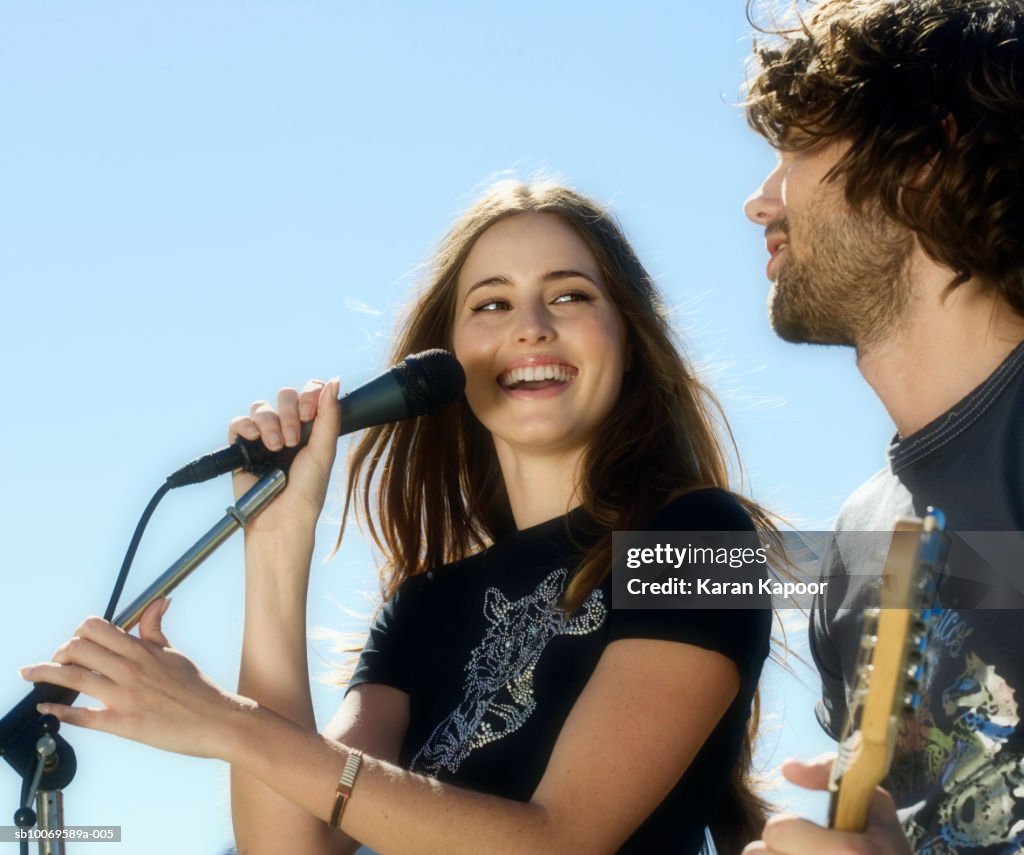 Young woman singing, man playing guitar