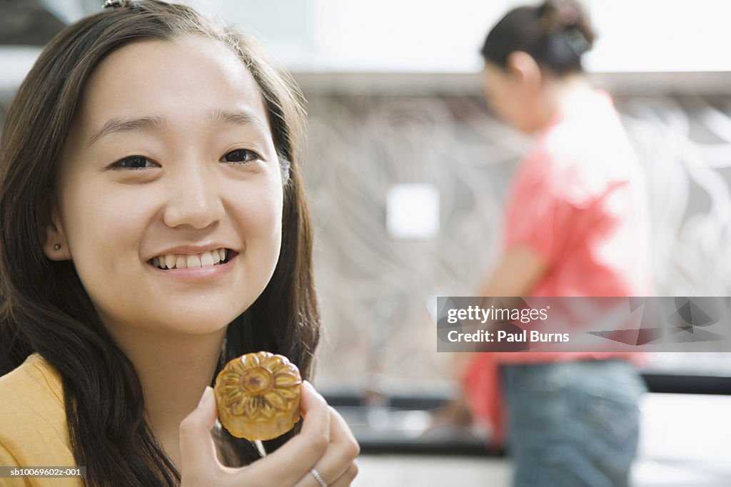 Young woman holding cookie, mature woman in background