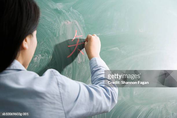 female teacher writing on  blackboard, rear view - niet westers schrift stockfoto's en -beelden