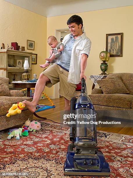 father holding baby boy (6-11 months) and vacuuming in living room - calção - fotografias e filmes do acervo