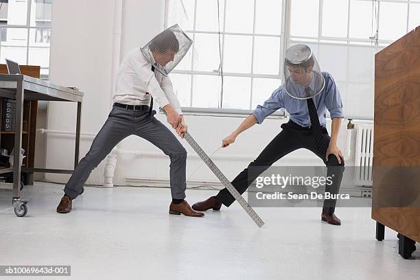 two men in office, playing sword fighting using large rulers - sport office foto e immagini stock