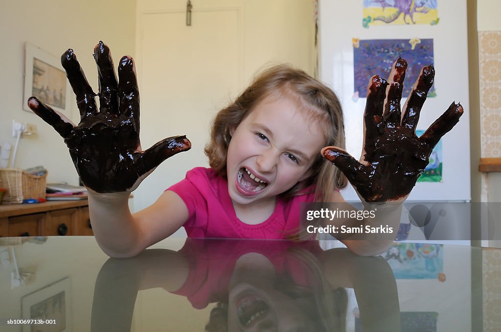 Girl showing hands with chocolate sauce