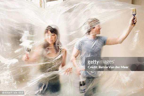 woman and man tangled in plastic painting sheet - couple trapped stock pictures, royalty-free photos & images