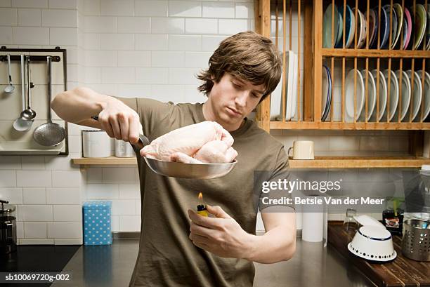 man cooking chicken in frying pan using cigarette lighter - cooked chicken stock pictures, royalty-free photos & images