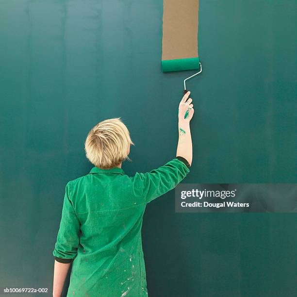 woman painting wall green, rear view - paint roller stock pictures, royalty-free photos & images