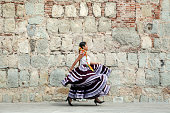 Mexico, Oaxaca, Istmo, young woman in traditional dress walking by stone wall
