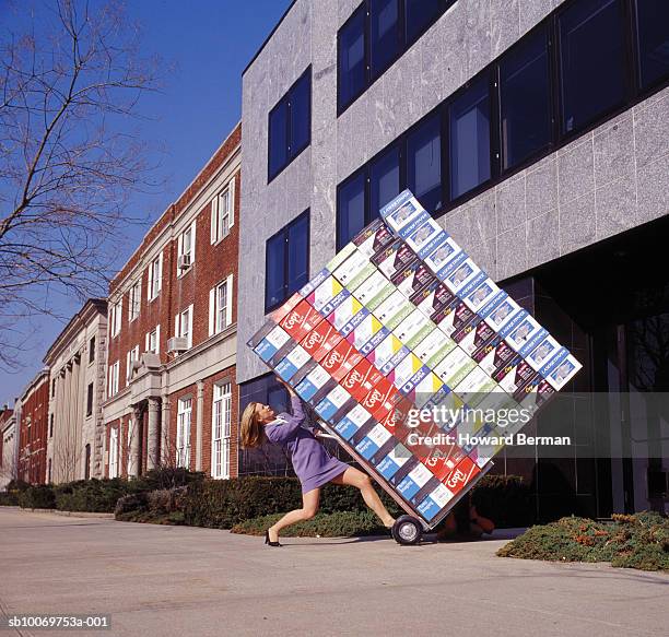 woman delivering heavy boxes, side view - jambes écartées photos et images de collection