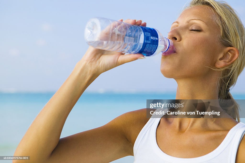 Young woman drinking water from bottle, eyes closed