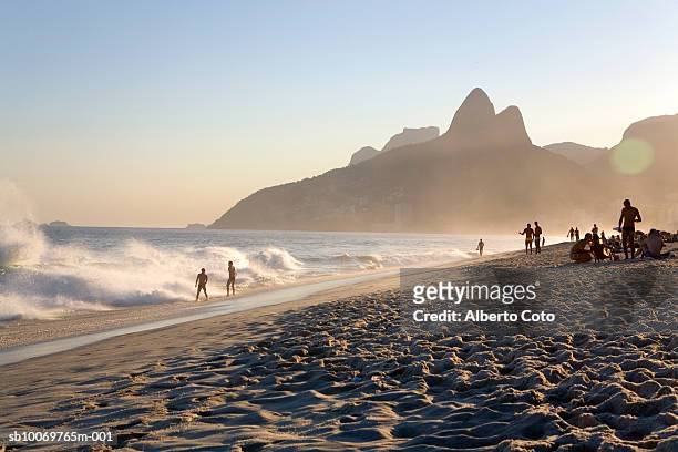 brazil, rio de janeiro, people on panema beach near dois irmaos at sunset - rio de janeiro photos et images de collection