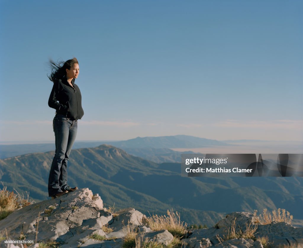 Woman standing on mountain top of mountain, side view