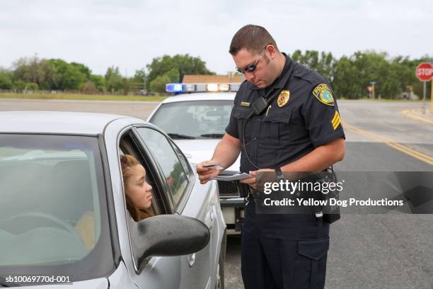 police officer examining license of teenage girl (16-17) - cuerpo de policía fotografías e imágenes de stock