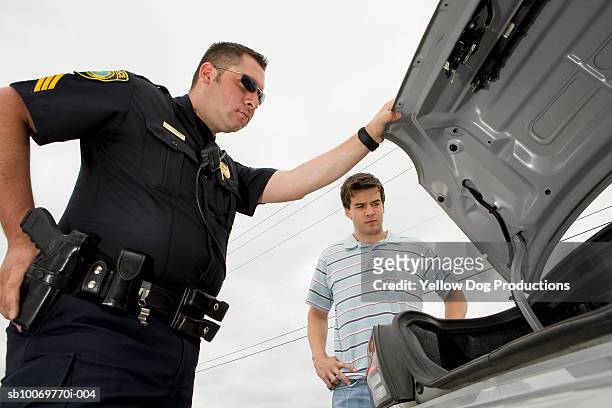 police officer searching in car trunk - cop car photos et images de collection