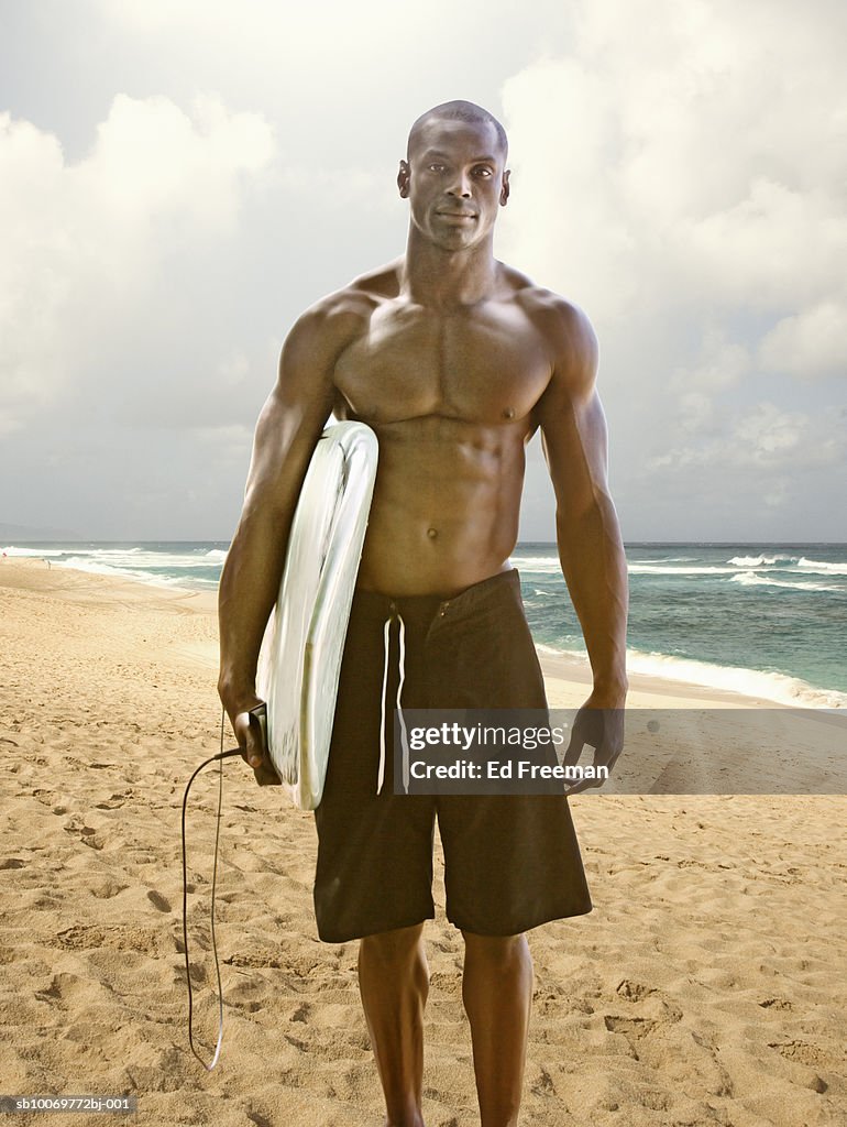 Young men with surfboard on beach, portrait