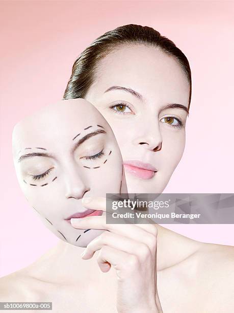 studio portrait of young woman holding face (digital composite) - plastische chirurgie stockfoto's en -beelden