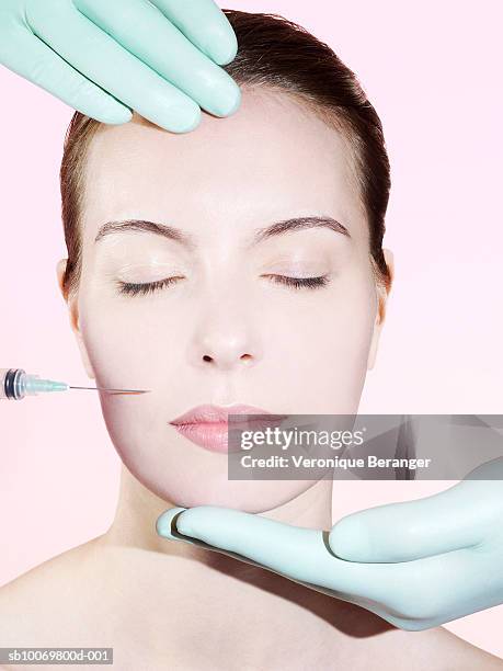 hands in surgical gloves holding woman's head - botox injections stock pictures, royalty-free photos & images