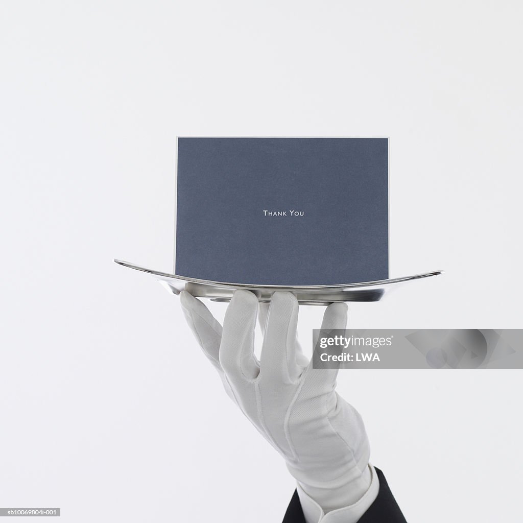 Waiter with greeting card on serving tray, close up of hand
