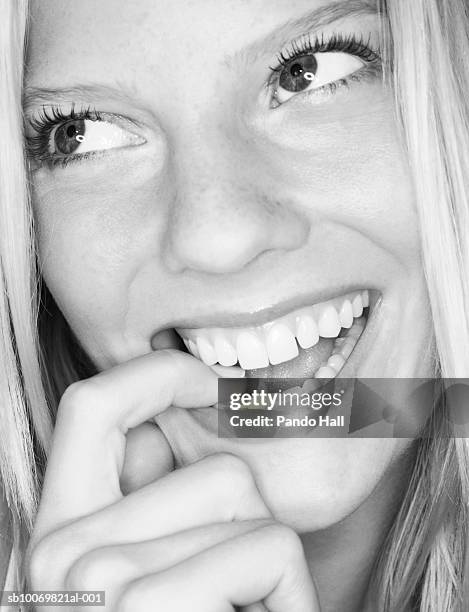 studio shot of young woman biting finger, close-up - usar la boca fotografías e imágenes de stock
