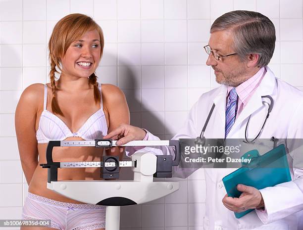 doctor checking patients weight, smiling - girls in bras fotos stock-fotos und bilder