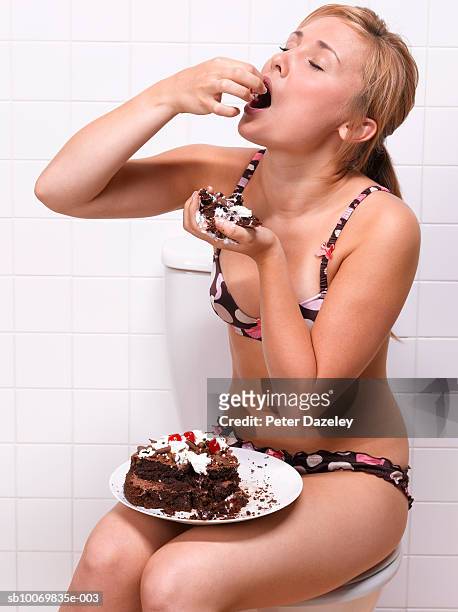 teenage girl (16-17) eating cake in bathroom - bulimia 個照片及圖片檔