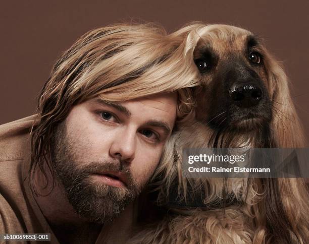 man with head under afgan hound's ear, portrait, studio shot - cuddling animals stock-fotos und bilder