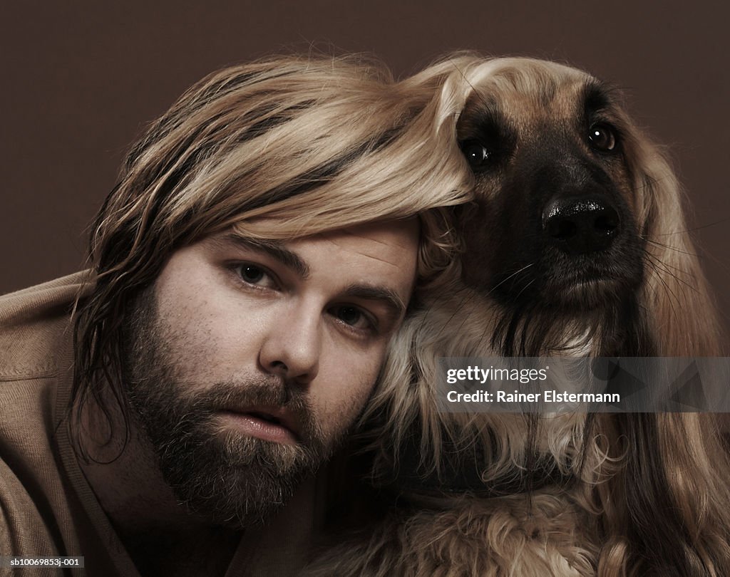 Man with head under Afgan Hound's ear, portrait, studio shot