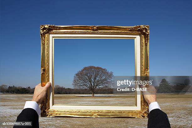 man holding picture frame in rural setting, view of hands - hand isoliert stock-fotos und bilder