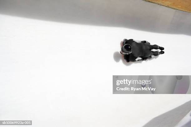 man on skeleton sled down ice track, high angle view - carrera de skeleton fotografías e imágenes de stock