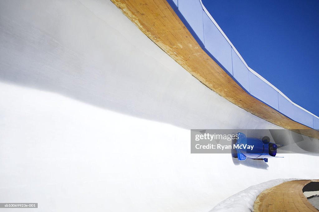 Blue Two-Man bobsled going down bobsled track.