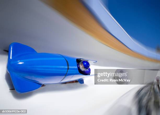 blue two-man bobsled going down bobsled track, blurred motion. - bob stock-fotos und bilder