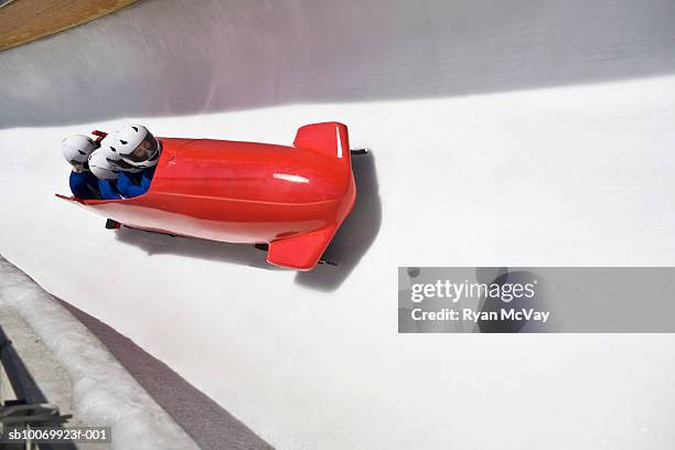 men racing red four-man bobsled down ice track - bobsleigh stock pictures, royalty-free photos & images