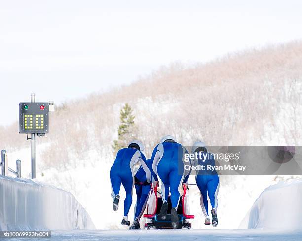 four man team launching bob-sleigh, rear view - bobsled stock pictures, royalty-free photos & images