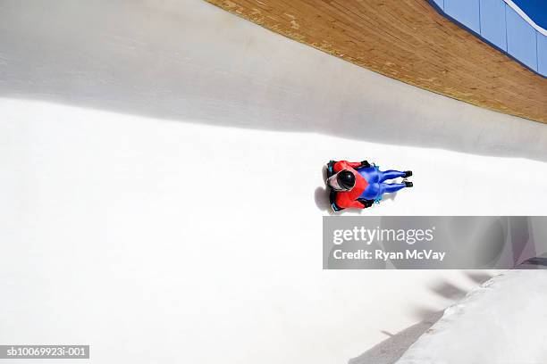woman on skeleton sled down ice track, high angle view - carrera de skeleton fotografías e imágenes de stock
