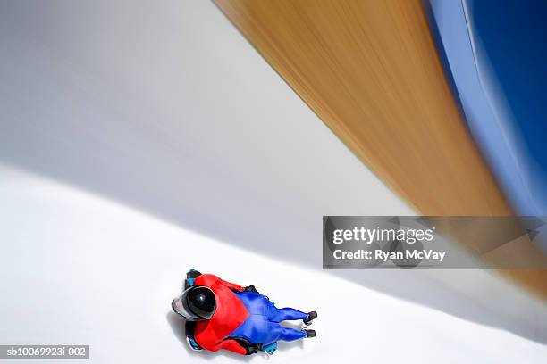 woman skeleton athlete on sled racing down ice track, blurred motion, low angle view - carrera de skeleton fotografías e imágenes de stock