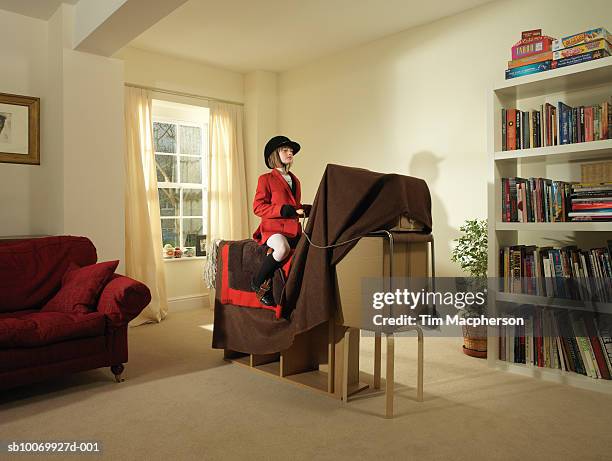 girl (8-9) pretending to ride horse made of furniture and blanket - shelf strip stock pictures, royalty-free photos & images
