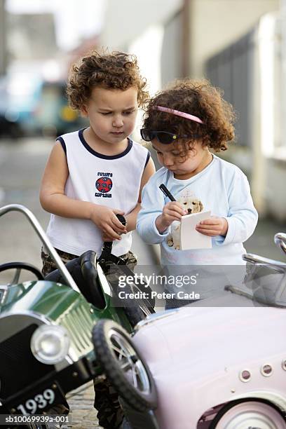 boy and girl (2-3) standing by toy car on street - crashes plymouth stock pictures, royalty-free photos & images