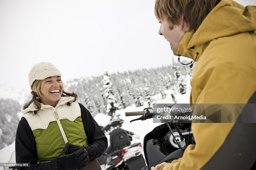 Couple with snow mobiles in mountains