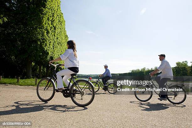 three people riding bicycle in park - versailles foto e immagini stock