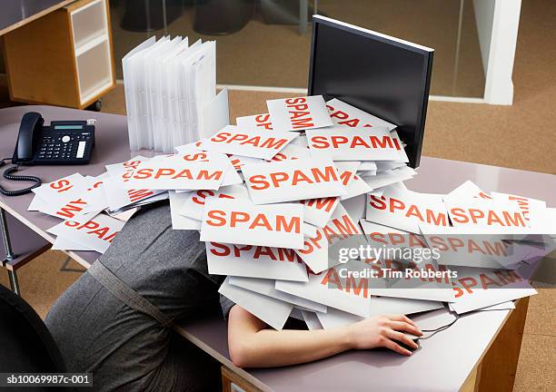 young businesswoman at office desk with pile of spam envelopes - e mail spam stockfoto's en -beelden