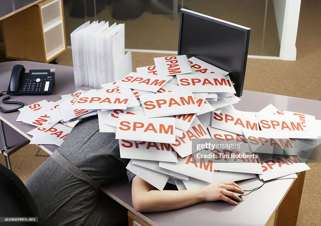 Young businesswoman at office desk with pile of spam envelopes