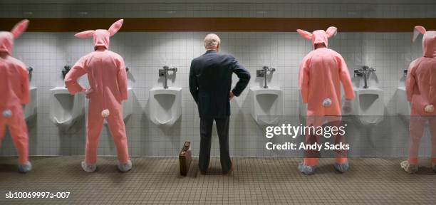 businessman and four men wearing rabbit costume standing at urinal, rear view (digital composite) - rabbit costume stock pictures, royalty-free photos & images