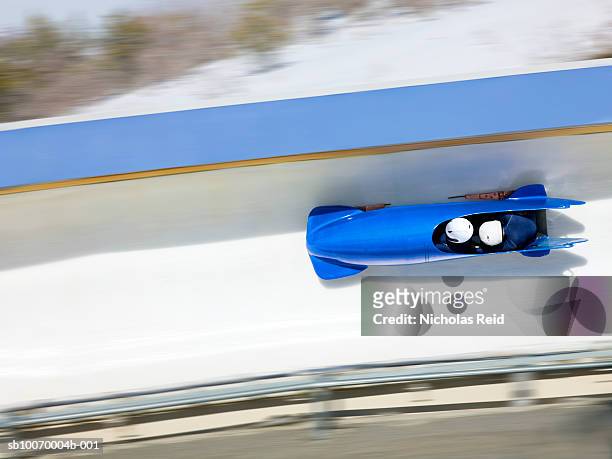 two men bobsled racing down track, view from above (blurred motion) - bobsleigh team stock-fotos und bilder