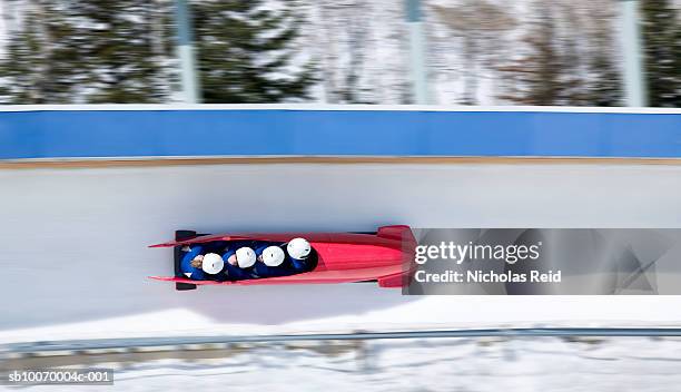 four men bobsled racing down track, view from above (blurred motion) - bob stock-fotos und bilder