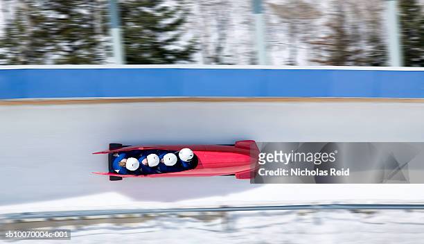 four men bobsled racing down track, view from above (blurred motion) - bobsleigh stockfoto's en -beelden